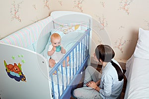 Mom and kid playing on the bed, smiling and laughing. Mother tic