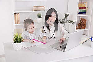 Mom and kid using laptop together and teaching in internet.