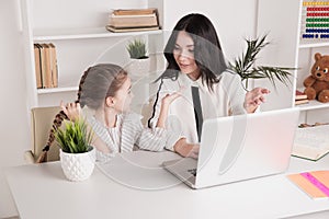 Mom and kid using laptop together and teaching in internet.