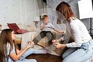 Mom and kids have fun in the bedroom and tickle each other`s feet. The older sister helps tickle the legs of the younger