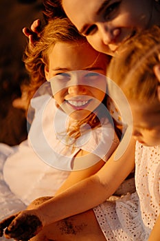 Mom with kids sitting on sand, beach by sea. relationship parents with children