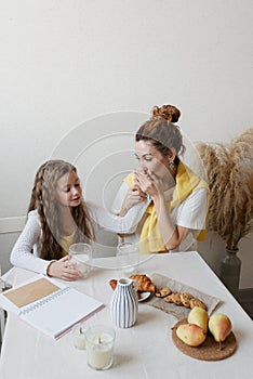 Mom kisses her daughter\'s hand at breakfast. Mother and daughter have breakfast with milk and cookies