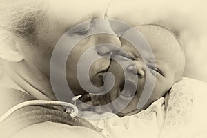 Mom kisses a newborn baby, vintage photo with toning