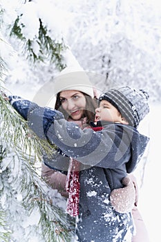 Mom kissing little stylish smiling happy cute boy, kid. Lovely family walking,activity in beautiful winter forest, park.Trees