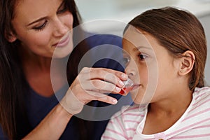 Mom knows best. a caring mother giving her sick little girl some medicine.