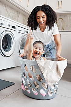 Mom, laundry and girl kid in basket by washing machine for cleaning, bonding or comic time in house. Crazy fun, mother