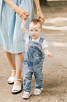 Mom leads by the hand of a little daughter. Infante learns to walk