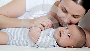 Mom lies in bed with a newborn who yawns