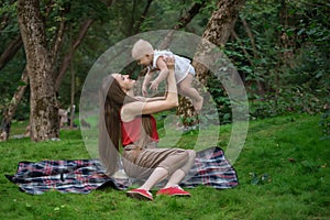 Mom lifted up the baby in her arms. Family picnic on the nature. Carefree maternity