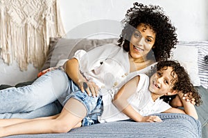 Mom and little cute curly girl spend time together, hugging and kissing each other