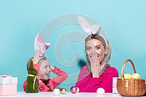 Mom with little cute girl are preparing for Easter. Mother and daughter wearing bunny ears are kissing. Easter banner