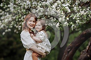 Mom and little daughter in the apple orchard