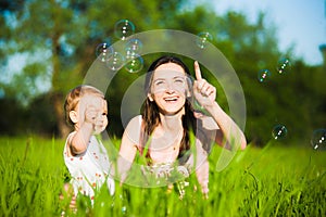 Mom and little daughter cheerfully catching soap bubbles photo