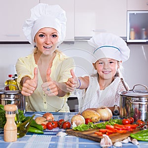 Mom and little daughter cooking vegeterian dish indoors