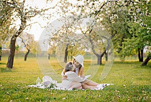 Mom and little daughter are looking at a family album with photos in the summer in the garden