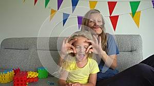 Mom and little daughter pretending man male guy making mustache with hair