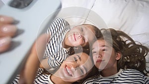 Mom, little daughter and son take a selfie while lying on the floor.
