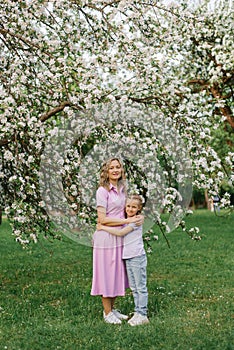 Mom and little daughter are walking through a blooming spring garden