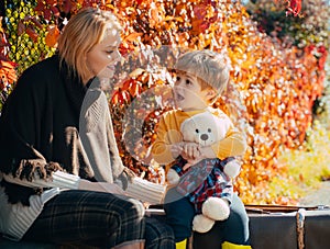 Mom little son communicate autumn foliage background. Trustful relations. Parenthood and upbringing. Love and trust