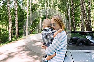 Mom and little son in a convertible car. Summer family road trip to nature