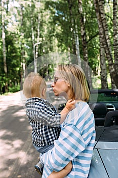 Mom and little son in a convertible car. Summer family road trip to nature