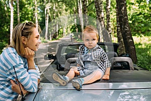 Mom and little son in a convertible car. Summer family road trip to nature