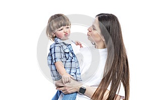 Mom and little son laugh and hug. A young brunette with long hair in a white T-shirt and jeans with a boy in jeans and a blue