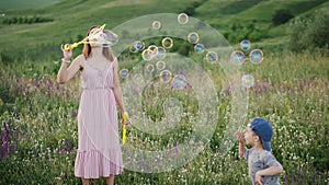 Mom with little son play with soap bubbles in nature