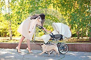 Mom looks at the baby in the stroller. Outdoors.