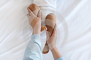 Mom Making Development Gymnastics With Black Baby Lying On Bed At Home