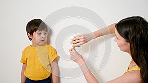 Mom measures the growth of a boy with a ruler with a son