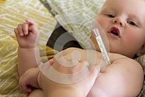 Mom measures the temperature of her baby with a mercury thermometer