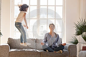 Mom meditating on couch ignore kid jumping near