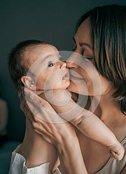 Mom, mummy, young mother with little baby daughter. Mum kissing and hugging child. Newborn cute happy girl smiling in