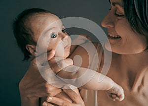 Mom, mummy, young mother with little baby daughter. Mum kissing and hugging child. Newborn cute happy girl smiling in