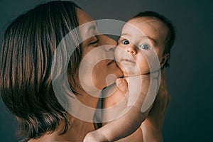 Mom, mummy, young mother with little baby daughter. Mum kissing and hugging child. Newborn cute happy girl smiling in