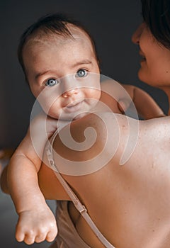 Mom, mummy, young mother with little baby daughter. Mum kissing and hugging child. Newborn cute happy girl smiling in