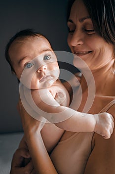 Mom, mummy, young mother with little baby daughter. Mum kissing and hugging child. Newborn cute happy girl smiling in