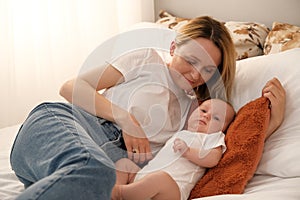 mom with a newborn baby lies on the bed. mother kisses the child. mother's love