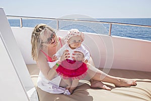 Mom with newborn daughter sunbathe on a yacht in the sea