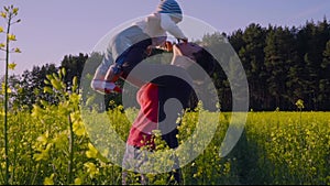 Mom played with the baby in the rapeseed field and throws it Slow motion