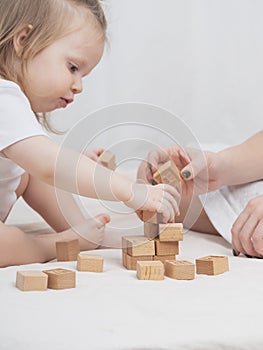 Mom is playing with a child, building a house out of wooden eco-friendly cubes, close-up. The concept of early