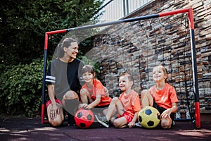 Mom playing football with her children, dressed in football jerseys. The family as one soccer team. Family sports