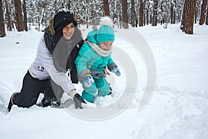 Mom plays with the child in the snow.