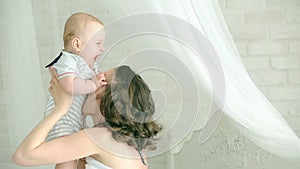 Mom plays with child. Young family. Six-month child and mother. Happy mom. Mother and son having fun. The child smiles.