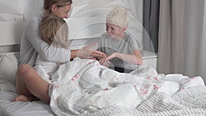 Mom plays with the children, son and daughter in the morning in her bed