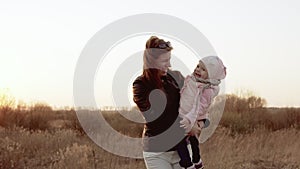 Mom plays with daughter, circling her, both laughing. Slo-mo shot