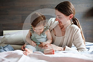 Mom plays with her little daughter in the bedroom. Gentle hugs and fun.