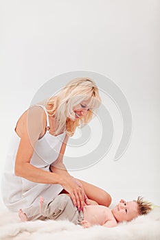 Mom plays with her little lying son on a white background