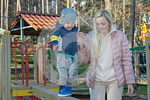 Mom plays with her son on the playground in the forest in autumn